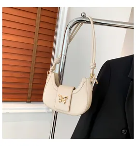 Chic white crescent shoulder bag with golden butterfly clasp and knotted strap details.