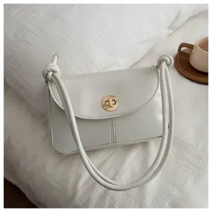 Detailed view of white minimalist shoulder bag with twist lock and knot handle design.