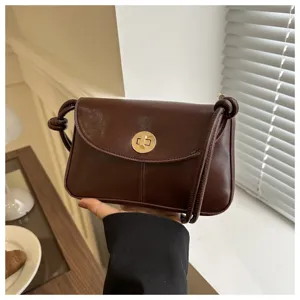 Close-up detail of retro brown small shoulder bag with gold twist lock and strap knot.