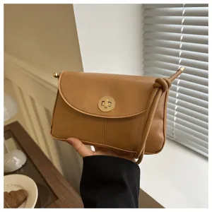 Detail shot of the vintage brown square crossbody bag, highlighting golden lock and texture.