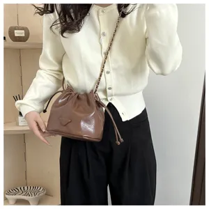 Brown leather bucket bag with chic chain strap, versatile winter crossbody and shoulder bag style.