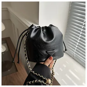 Black leather bucket bag detail view featuring gold chain strap and drawstring closure.