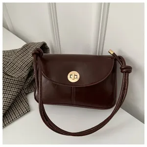Detail view of dark brown vintage shoulder bag with metal twist lock and chic strap.