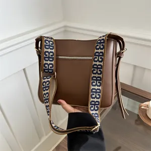 Brown women shoulder bag with wide monogram strap, casual commute bucket bag front view.