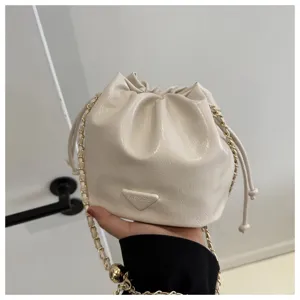 White leather bucket bag detail view featuring a chic metal chain strap and drawstring.