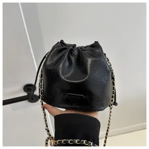 Detailed view of a stylish black bucket bag featuring gold chain strap and chic design.