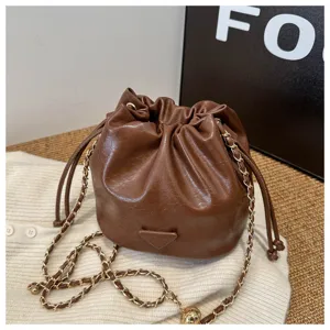 Brown leather bucket bag detail, stylish chain strap and drawstring closure design for women.