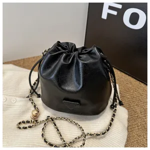 Detailed view of the black PU leather bucket bag featuring a trendy chain strap and drawstring.