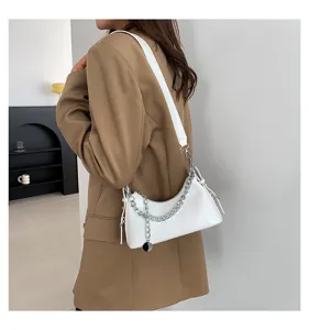 Details of white underarm shoulder bag with silver chain accessory in modern indoor setting fashion