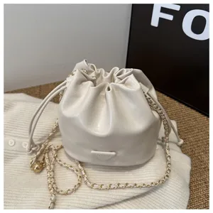 Chic minimalist white bucket bag with gold chain strap, stylish small crossbody bag for women.