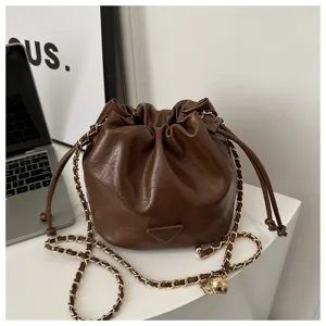 Brown leather bucket bag detail featuring golden chain strap and drawstring closure design.