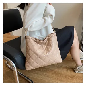 Detailed view of stylish beige quilted shoulder bag with elegant gold chain for daily use.