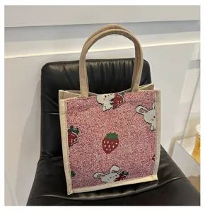 Detailed view of the cute strawberry and bunny woven canvas tote bag with sturdy dual handles.