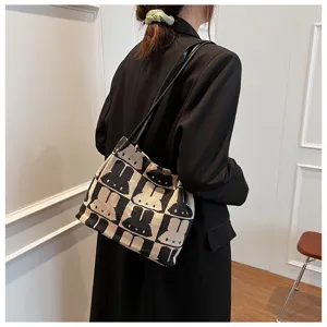 Close-up detail of stylish black and white knitted rabbit pattern tote bag worn on shoulder.