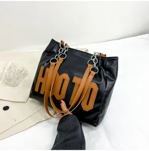 Black PU leather tote shoulder bag for women with brown handles, chain design and letters.