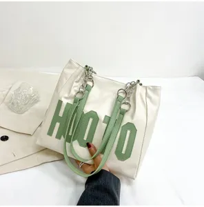 Fashion large capacity white tote bag with green letter decoration, stylish shoulder bag for use.