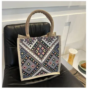 Detailed view of ethnic geometric woven jute tote bag showing colorful patterns and handles.