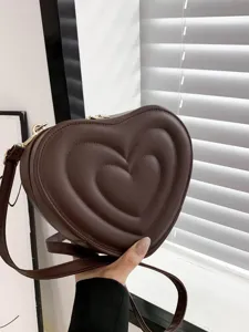 Close-up detail of the stylish dark brown heart-shaped crossbody bag with soft texture.
