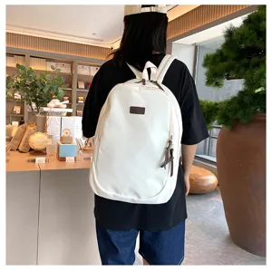 Detail view of a solid white casual backpack worn on the back, featuring a brown leather patch.