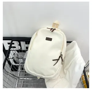 Detailed view of casual white canvas backpack with brown accents, shown in shopping cart setting.