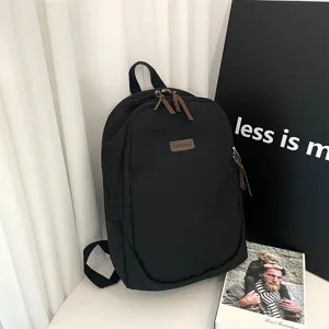 Minimalist black canvas backpack for daily casual travel and student use, front view detail.