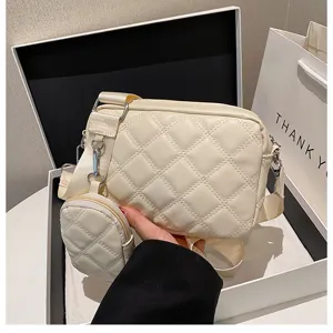 Detailed view of the elegant beige quilted crossbody bag with small pouch and wide strap.