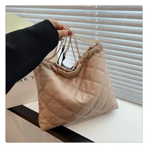 Detailed view of quilted chain shoulder bag, soft PU leather with elegant golden metallic strap.