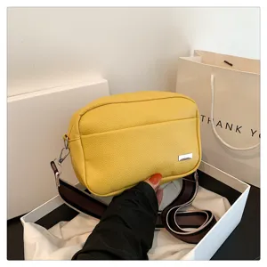 Detail view of yellow PU leather crossbody bag, stylish wide strap and compact square design.