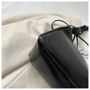 Black faux leather pleated shoulder bag detail shot, minimalist cloud dumpling handbag style.