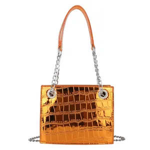 Orange metallic crocodile pattern small square handbag detail, shiny chain strap close-up view.