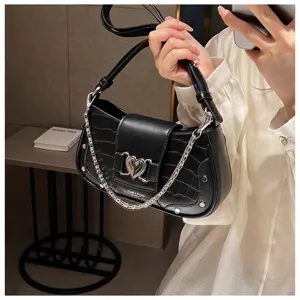 Close-up detail of black PU leather underarm bag with crocodile texture and cute heart chain.