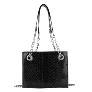 Sac à main bandoulière en cuir verni noir motif crocodile avec chaîne et anneaux métalliques.