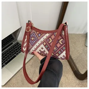 Close-up detail of ethnic woven pattern shoulder bag with burgundy leather trim and strap.