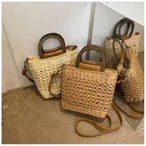 Detailed close-up view of stylish straw woven bucket bag with wood handle and brown strap.
