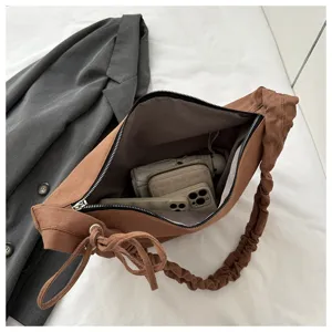 Detail view of the brown canvas pleated hobo bag showing spacious interior and unique strap.