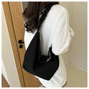 Detail view of a stylish black canvas hobo shoulder bag featuring a chic ruched strap.
