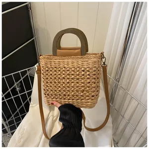 Straw woven bucket bag detail, handmade straw texture with wooden handle and brown strap.