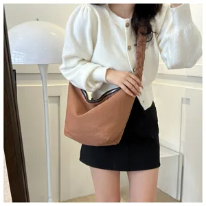 Minimalist brown canvas crossbody dumpling bag detail, showcasing pleated shoulder strap design.