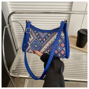 Detailed view of a trendy ethnic woven underarm shoulder bag with blue leather trim.