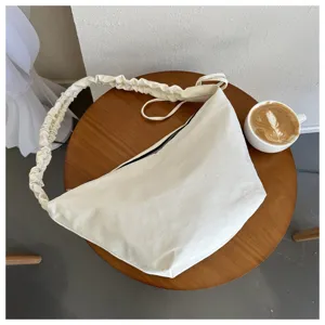Minimalist canvas shoulder bag detail, stylish gathered strap, casual cream dumpling tote design.