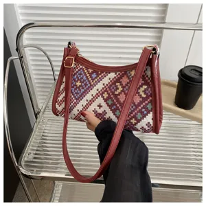 Detail shot of ethnic woven shoulder bag, vibrant geometric pattern with red leather trim and strap.