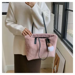 Detail shot of stylish pink faux fur shoulder bag with black leather handles and cute charm.