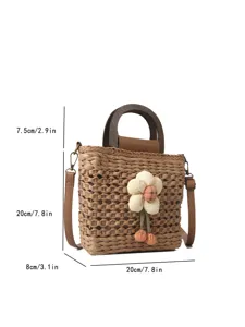 Straw woven bucket bag detail showing wooden handle, fabric flower charm, and exact dimensions.