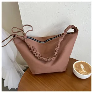 Detail shot of the brown canvas pleated shoulder dumpling bag, showcasing texture and design.