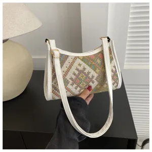 Close-up detail shot of an ethnic geometric woven hobo shoulder bag with white leather trim.