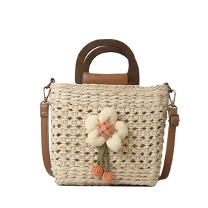 Detailed view of fashionable woven straw handbag with wooden handle and floral accent.