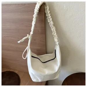 Detailed view of the casual off-white canvas shoulder bag with pleated strap and zipper closure.