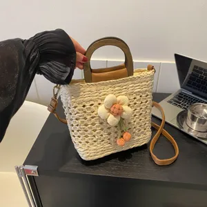 Straw woven bucket bag with wooden handle and cute plush flower decoration, casual summer tote.