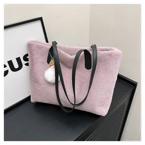 Detail shot of a stylish pink plush tote bag with black handles and cute charm for women.
