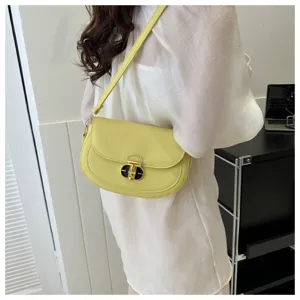 Light yellow shoulder bag detail showcasing minimalist design and metal lock closure for daily wear.